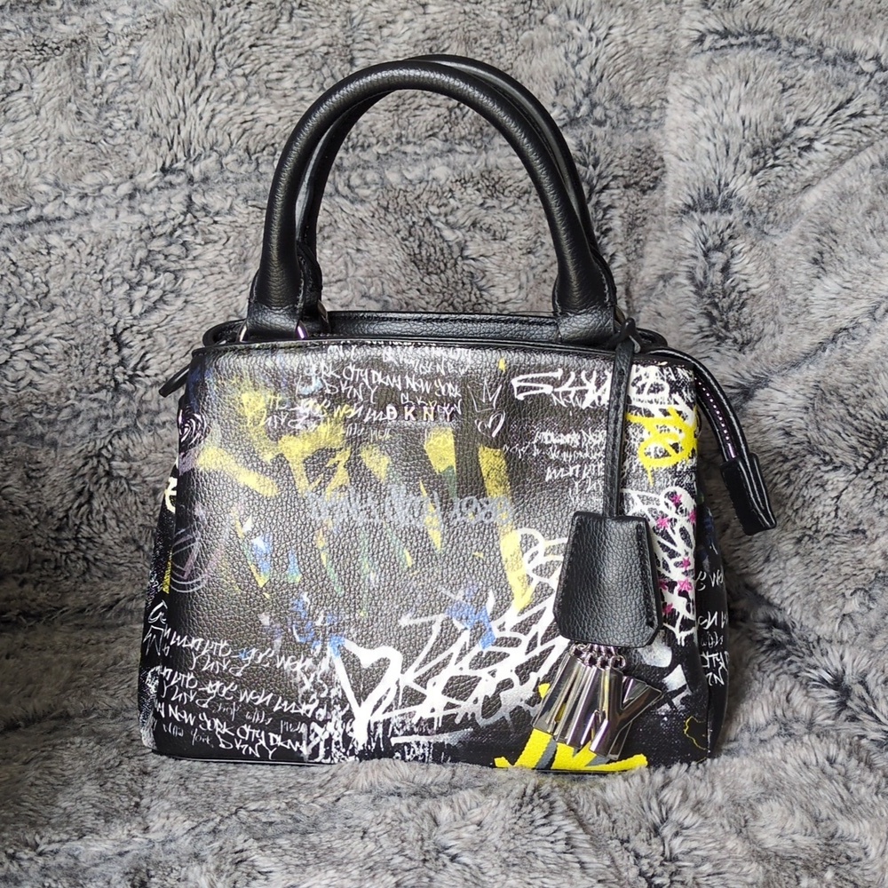 DKNY Paige small satchel crossbody handbag with a graffiti print.​